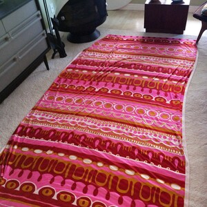 May include: A pink and orange patterned fabric with a geometric design. The fabric has a striped pattern with circles, ovals, and wavy lines.
