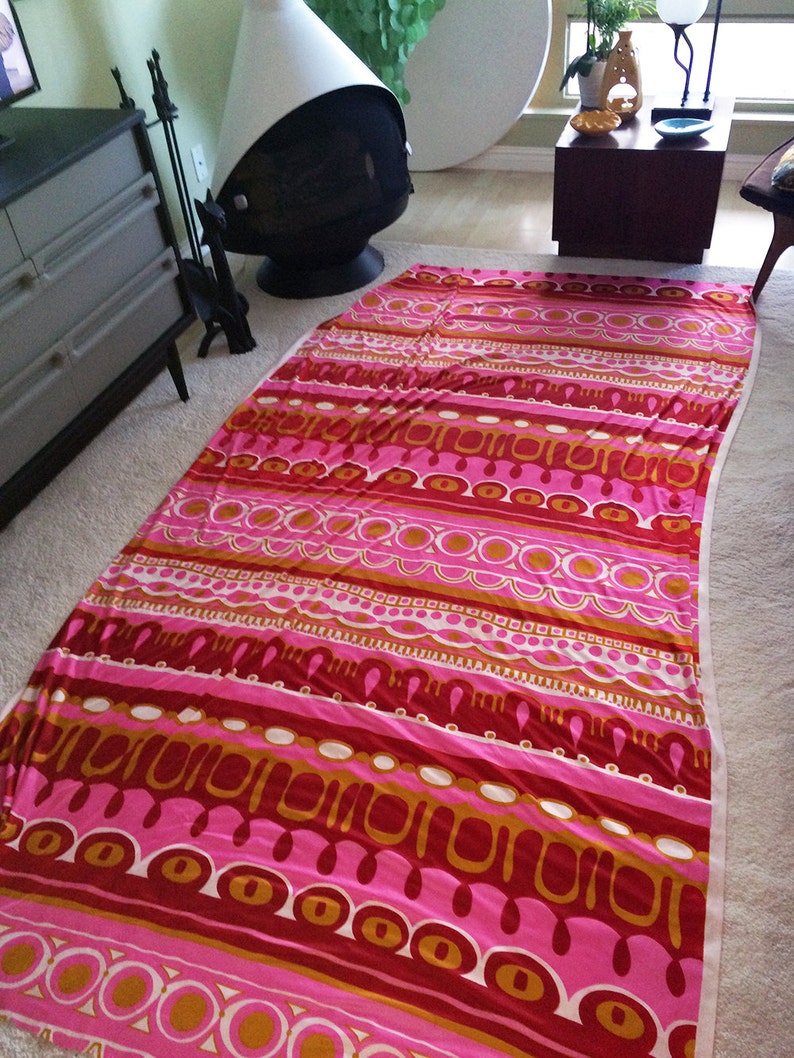 May include: A pink and orange patterned fabric with a geometric design. The fabric has a striped pattern with circles, ovals, and wavy lines.