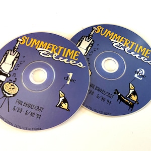 Pode incluir: Dois discos compactos azuis com o título "Summertime Blues" impresso em amarelo. Os discos são etiquetados como "disco 1" e "disco 2" e incluem o texto "For Broadcast 5/28 - 5/30 '94" e "© 1994 Global Satellite Network".