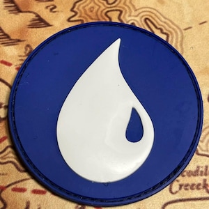 May include: A circular blue patch featuring a white water droplet design. The patch has a black border and is set against a map background. The droplet is a stylized representation of water.
