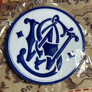 Peut inclure: Un embl&egrave;me rond, blanc et bleu, avec un motif stylis&eacute;. L'embl&egrave;me a une bordure bleue et un motif central bleu. L'arri&egrave;re-plan semble &ecirc;tre une carte.