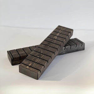 Puede incluir: Dos expositores de madera teñida oscura. Cada soporte tiene una base rectangular con varias ranuras espaciadas en la superficie superior. Los soportes están diseñados para sostener y exhibir artículos. La veta de la madera es visible.