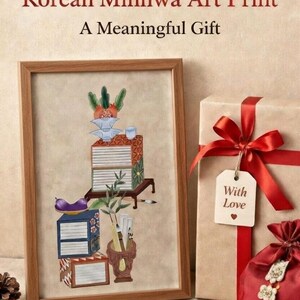 May include: A framed Korean Minhwa art print with a traditional still life scene. The image includes stacks of books, a vase with brushes, and a gift box tied with a red ribbon. Text on the image reads "Symbol of Wisdom & Prosperity" and "A Meaningful Gift."