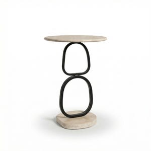 May include: A modern side table with a round, light-colored top and a black, open, geometric base. The base consists of two connected, oval shapes and a stone-like, oval base. The table is a stylish accent piece.