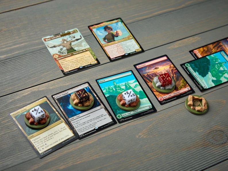 May include: Several Magic: The Gathering trading cards are displayed on a wooden surface. Each card has a unique illustration and text. Dice and tokens are placed on some cards, enhancing the game play.