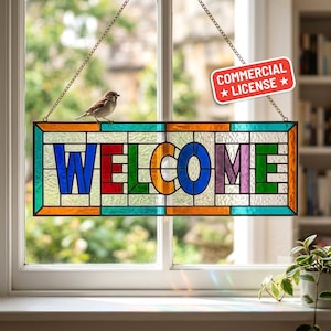 May include: A stained glass window hanging with the word "WELCOME" in colorful letters. The window is framed in orange, green, and blue. A small bird perches on top of the window, which is suspended by a chain.