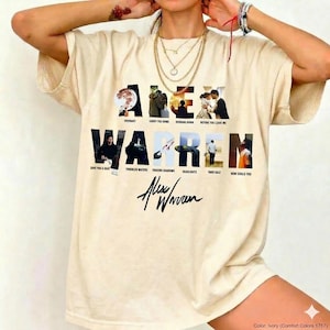 Könnte beinhalten: Elfenbeinfarbenes T-Shirt mit dem Namen "ALEX WARREN" in großen, schwarzen Großbuchstaben, in die verschiedene Bilder integriert sind. Unter dem Namen befindet sich die Unterschrift des Künstlers. Songtitel sind ebenfalls aufgedruckt.