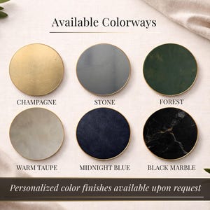 Op de afbeelding: Afbeelding met zes ronde onderzetters met gouden randen, elk met een andere kleur en textuur. Kleuren zijn champagne, steen, bosgroen, warm taupe, middernachtblauw en zwart marmer. De tekst luidt "Available Colorways" en "Personalized color finishes available upon request."