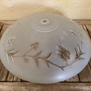 May include: A frosted glass lampshade with a floral design. The shade is white with a subtle gray tint and features delicate etched branches and clusters of berries.