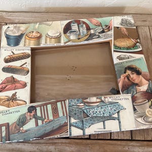 May include: Vintage rectangular picture frame with illustrations from Wills' Cigarettes. The frame features various images, including food preparation and a woman. The frame is made of cardboard and has a wooden backing.