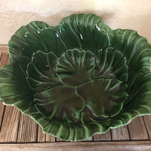 May include: A green ceramic bowl shaped like a cabbage with detailed leaf texture.