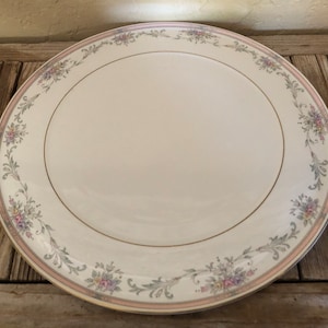 May include: A white ceramic serving platter with a gold rim and a floral design in shades of pink, green, and gray.