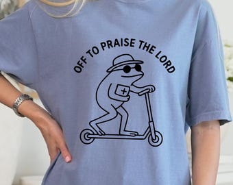 Camiseta "Alabar al Señor" con diseño de rana, colores cómodos, fe y humor cristiano.
