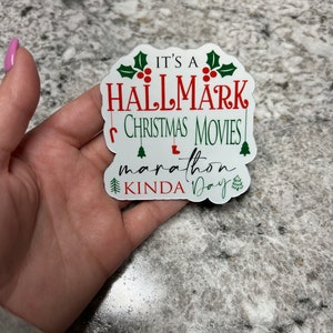 May include: White sticker with green holly and red berries. The text reads "It's a Hallmark Christmas Movies Marathon Kinda Day".