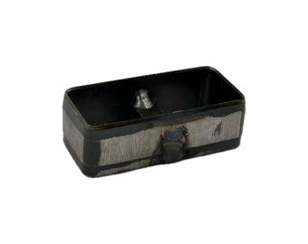 May include: A rectangular metal cutting die with a hollow center and rounded corners. The exterior features a dark, brushed steel finish with visible weld marks and a small, centered metallic stud on the inner base of the frame.