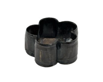 May include: A black, four-lobed flower-shaped cookie cutter with a smooth, continuous metal wall. The object features a rounded, symmetrical design with four distinct petals and an open center, showcasing a dark, uniform finish throughout.