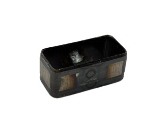 May include: A rectangular metal component with a dark, oxidized finish and visible brushed silver-toned vertical panels on the sides. The hollow interior features a small, metallic attachment point centered at the base of the frame.