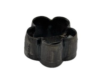 May include: A small, black, flower-shaped metal cutter with a hollow center and a textured, dark finish. The object features five rounded petals forming a continuous loop, with a visible metal seam connecting the ends of the strip of material.