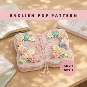 Könnte beinhalten: Eine rosa gehäkelte, schmetterlingsförmige Tasche mit bunten Blumenverzierungen. Die Tasche hat einen Kordelverschluss und ist von Büchern umgeben. Der Text auf dem Bild lautet "ENGLISH PDF PATTERN" und "BUY 1 GET 1".