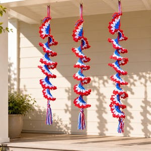Pode incluir: Três decorações espirais suspensas, feitas em crochê vermelho, branco e azul. Cada espiral tem uma borla na parte inferior e é suspensa por uma fita vermelha. O crochê apresenta uma borda ondulada, criando um visual festivo e patriótico.