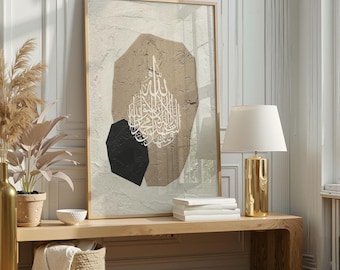 May include: Framed abstract art print featuring a beige textured background with a brown and black geometric design. White Arabic calligraphy is centered on the artwork. The artwork is displayed on a wooden bench with a gold lamp.