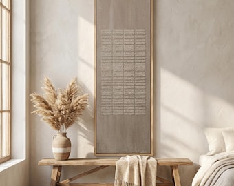 May include: A neutral-toned interior scene featuring a large, rectangular artwork with a textured, geometric design. A wooden bench holds a beige throw blanket. A vase with dried pampas grass sits nearby, enhancing the room's natural aesthetic.