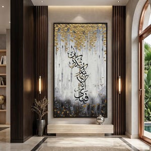 May include: Large abstract painting with gold leaf accents and black calligraphy on a white and gray background. The artwork is framed in black and hangs in a modern interior setting. The painting is a focal point in the room.