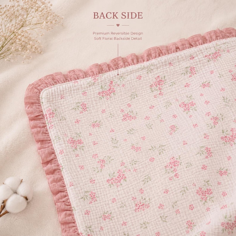 May include: A reversible baby blanket with a floral pattern. The blanket features a soft, white fabric with small pink flowers and green leaves. The border is a ruffled, dusty rose color. The text "BACK SIDE" is visible.
