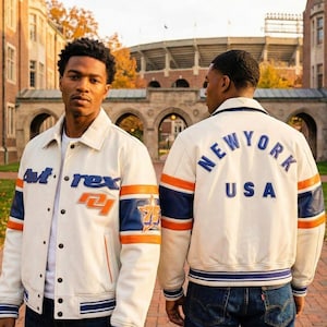 May include: Cream-colored leather jacket with blue and orange accents. The jacket features the text "At-rex" and "75" with a star graphic on the sleeve. The back of the jacket displays "NEW YORK USA" in blue lettering. The jacket has a striped hem and cuffs.