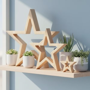 Puede incluir: Decoraciones de madera en forma de estrella de varios tamaños, exhibidas en una estantería de color claro. Pequeñas suculentas en macetas y otras plantas en macetas blancas y grises se colocan alrededor de las estrellas contra una pared azul claro.
