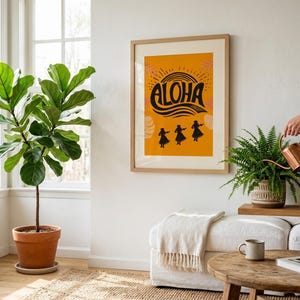 May include: A framed art print with the word "ALOHA" in black script on a yellow background, with silhouettes of dancers. A large potted plant and other greenery are in the room. A person is watering a plant with a copper watering can.