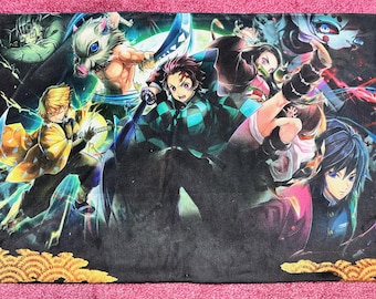 May include: A black blanket featuring multiple anime characters in action poses. The blanket has a pink border and a gold wave pattern at the bottom. The characters are in vibrant colors, with dynamic energy.