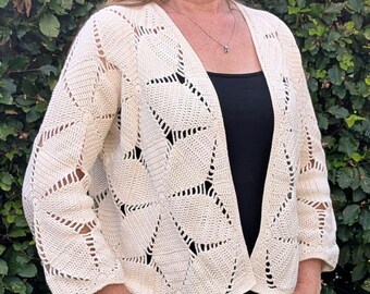 Puede incluir: Cárdigan de crochet color crema con frente abierto y un patrón geométrico. Las mangas de tres cuartos y el diseño abierto crean una silueta relajada. El cárdigan está hecho de un hilo suave y texturizado, perfecto para combinar.