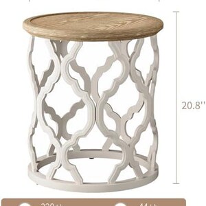 Puede incluir: Una mesa auxiliar redonda con una tapa de madera clara y una base calada blanca. La mesa tiene 47 cm de di&aacute;metro y 53 cm de altura. Tiene una capacidad central de 100 kg y una capacidad de borde de 20 kg.