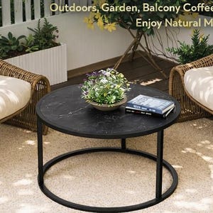 May include: A round black coffee table with a marble-like top and a black metal frame. Two wicker chairs with cream-colored cushions flank the table. The scene is set on a beige rug, with text that reads "Outdoors, Garden, Balcony Coffee Table Enjoy Natural Moment."