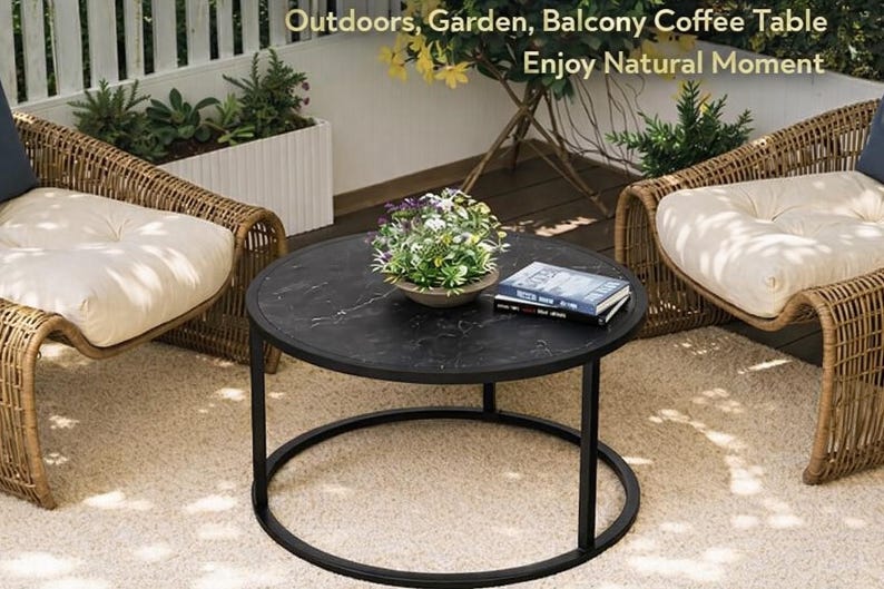 May include: A round black coffee table with a marble-like top and a black metal frame. Two wicker chairs with cream-colored cushions flank the table. The scene is set on a beige rug, with text that reads "Outdoors, Garden, Balcony Coffee Table Enjoy Natural Moment."