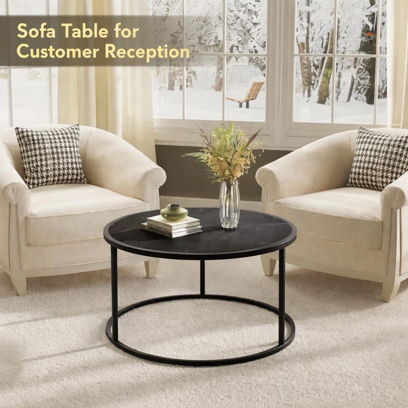 May include: A black round sofa table with a marble top and a black metal frame. The table is in front of two cream-colored armchairs with patterned pillows. The text "Sofa Table for Customer Reception" is at the top.