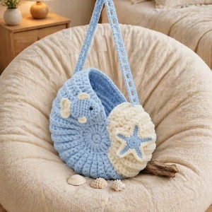 May include: A handmade crochet bag in a seashell design. The bag features a light blue and cream color scheme, with a starfish and fish embellishments. The bag has light blue straps and is sitting on a cream-colored beanbag chair.