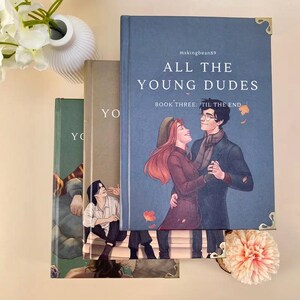 Puede incluir: Una pila de tres libros con el t&iacute;tulo "All The Young Dudes" en la portada. La ilustraci&oacute;n de la portada muestra a una pareja bailando. Los libros son en tonos azules, verdes y beige.
