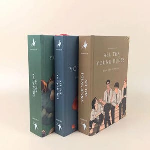 Puede incluir: Se muestran tres libros de tapa dura titulados "All The Young Dudes". Los libros son en tonos de verde, azul y marr&oacute;n. Las portadas presentan ilustraciones y texto, incluyendo "Book One Years 1-4" en el libro marr&oacute;n.