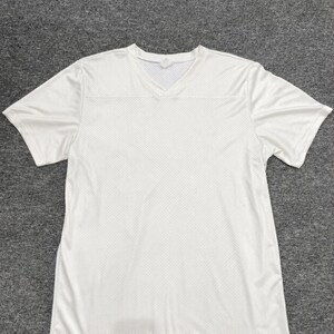 May include: A solid white short-sleeve athletic t-shirt featuring a V-neck collar and a breathable mesh fabric construction. The garment has a standard fit with short sleeves and a clean, unpatterned design throughout the entire front surface.