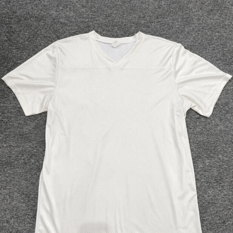 May include: A solid white short-sleeve athletic t-shirt featuring a V-neck collar and a breathable mesh fabric construction. The garment has a standard fit with short sleeves and a clean, unpatterned design throughout the entire front surface.