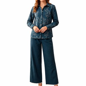 May include: A dark teal long-sleeved button-down shirt featuring a light-colored botanical line art pattern, paired with matching dark teal wide-leg trousers that have a subtle white trim along the bottom hem and brown leather slide sandals.