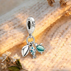 Könnte beinhalten: Ein silberner Charm-Anhänger mit dem eingravierten Wort "Explore", der einen Seestern und eine Sammlung von Charms zum Thema Ozean zeigt. Die Charms umfassen eine Muschel, einen Fisch mit blauen Schuppen und eine türkisfarbene Schildkröte. Der Charm ist für ein Armband oder eine Halskette konzipiert.