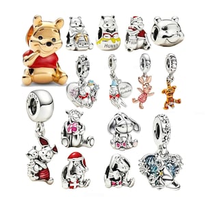 Könnte beinhalten: Eine Sammlung von silber- und goldfarbenen Metallanhängern mit Winnie Puuh-Figuren. Die Anhänger zeigen verschiedene Darstellungen von Puuh, Ferkel, Tigger und I-Aah, einige mit Emaille-Akzenten, hängenden Elementen und einer Gravur mit der Aufschrift HapBi Birthday.