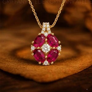 Puede incluir: Un collar con colgante de oro con un diseño floral. El colgante tiene cinco piedras preciosas rojas oscuras de talla ovalada que rodean una piedra preciosa central, redonda y transparente. Pequeñas piedras preciosas redondas y transparentes están engastadas alrededor de las piedras rojas. La cadena del collar es de oro.