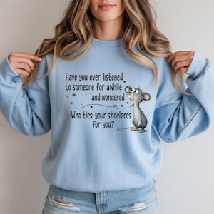 May include: A light blue sweatshirt with the text "Have you ever listened to someone for awhile and wondered Who ties your shoelaces for you?" A cartoon mouse is drawn next to the text.