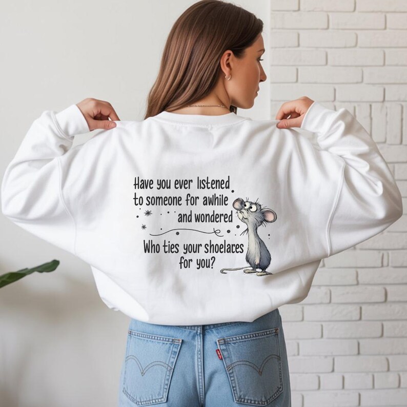 May include: White sweatshirt with the text "Have you ever listened to someone for awhile and wondered Who ties your shoelaces for you?" and a cartoon mouse. The sweatshirt is worn by a person wearing blue jeans.
