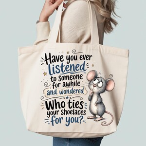 May include: A cream-colored canvas tote bag featuring a cartoon mouse with large ears and a thoughtful expression. The text reads: Have you ever listened to someone for awhile and wondered Who ties your shoelaces for you? with blue and black lettering.
