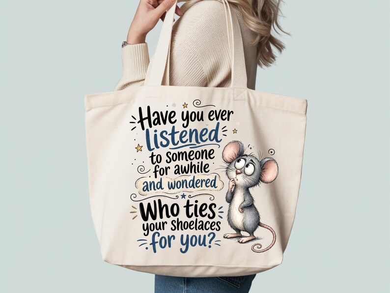 May include: A cream-colored canvas tote bag featuring a cartoon mouse with large ears and a thoughtful expression. The text reads: Have you ever listened to someone for awhile and wondered Who ties your shoelaces for you? with blue and black lettering.